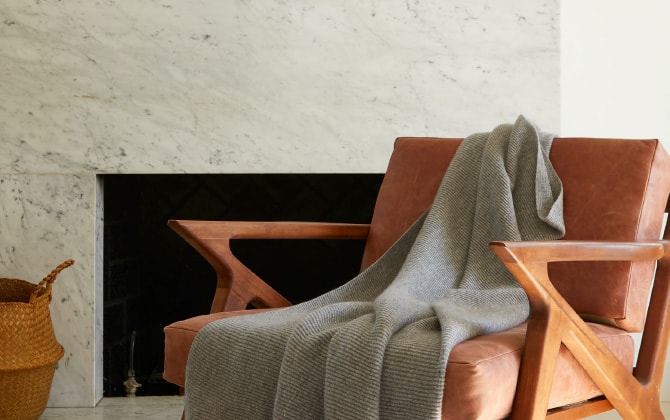 大理石のような壁の室内に木の手すりのソファとひざ掛けが置いてある様子