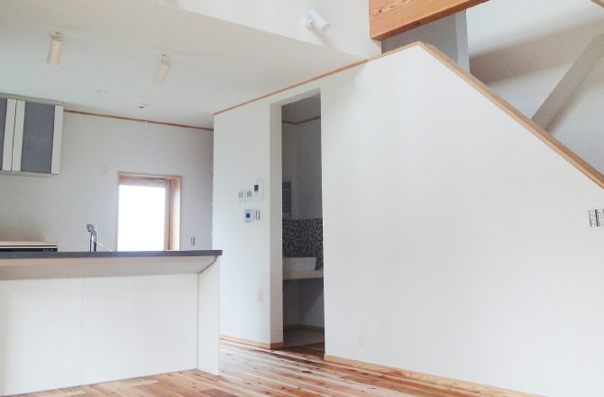 白い壁のキッチンと奥に洗面台がある様子