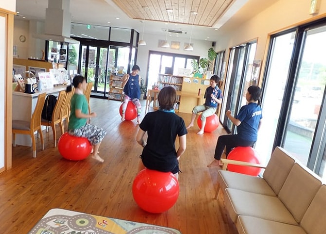 赤いバランスボールに座って輪になっているいる数人の女性